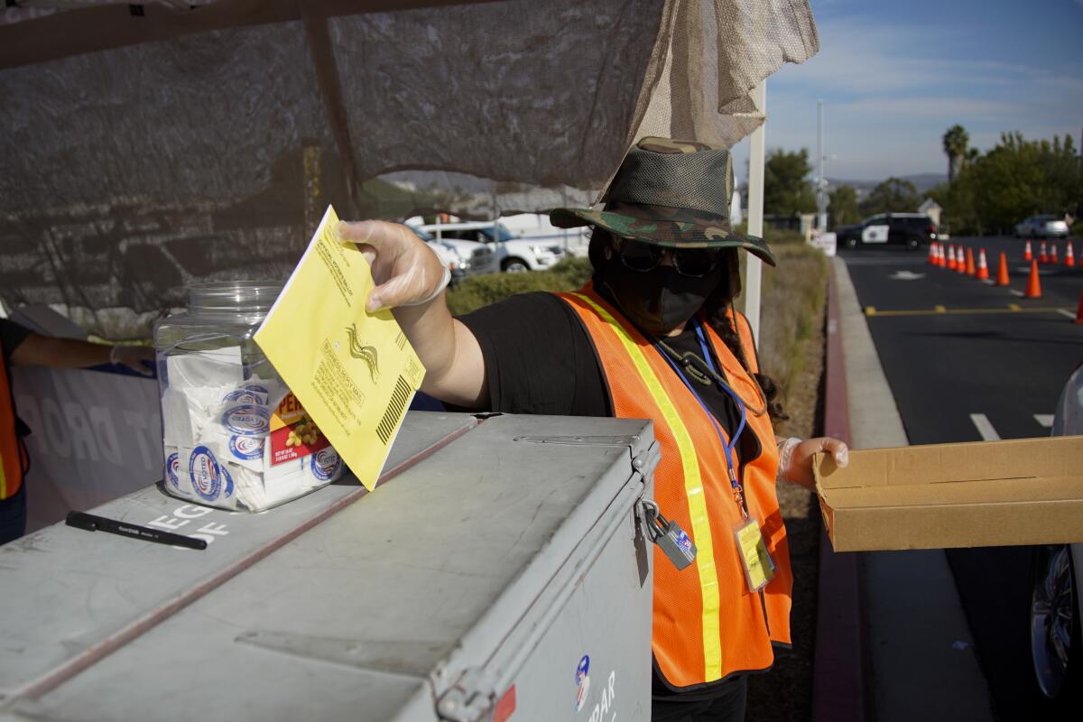 A poll worker drops a ballot into a box