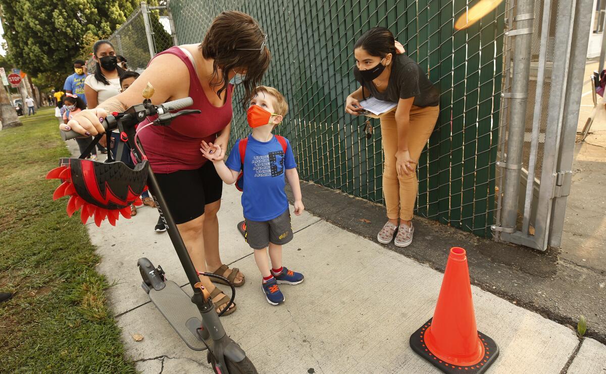 A mother holds her child's hand while checking in for school