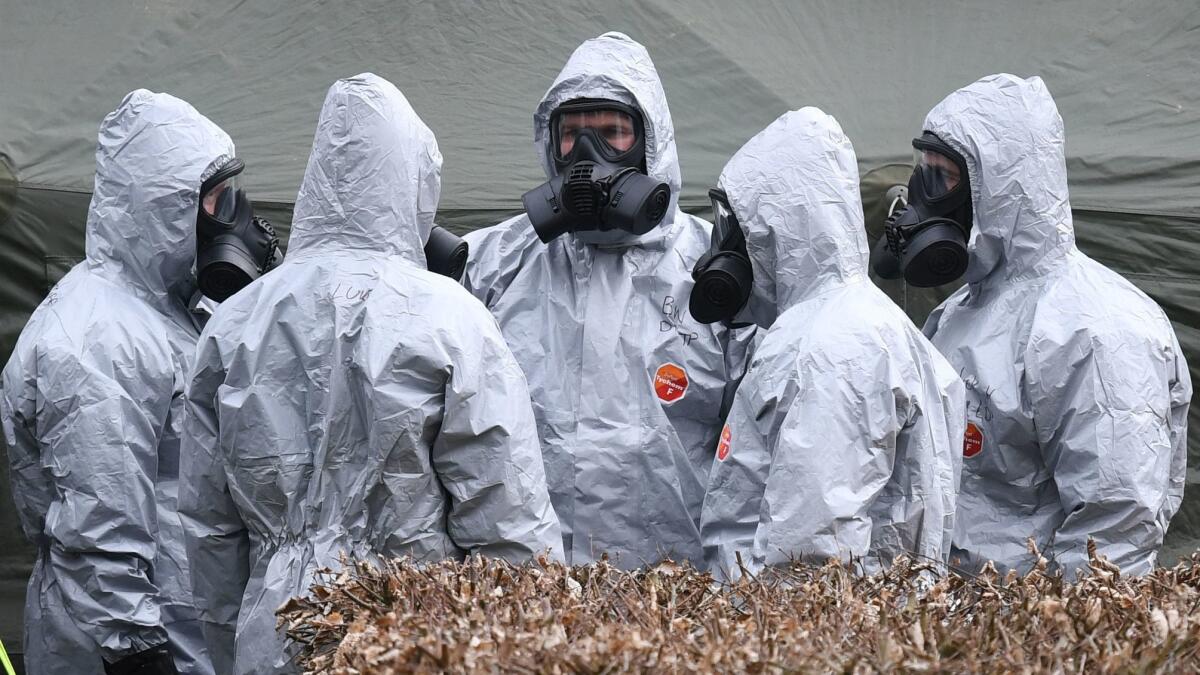 Military members in protective clothing prepare to remove vehicles from a parking lot in Salisbury, Britain.