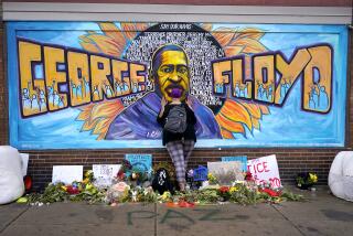 FILE - Damarra Atkins pays respect to George Floyd at a mural at George Floyd Square in Minneapolis, April 23, 2021. Minneapolis will buy the boarded-up Speedway gas station at George Floyd Square, the City Council decided unanimously on Thursday, Dec. 8, 2022. The area has become a protest site since Floyd, a Black man, was killed there by a white police officer in May 2020, sparking a national reckoning on racial injustice. (AP Photo/Julio Cortez, File)