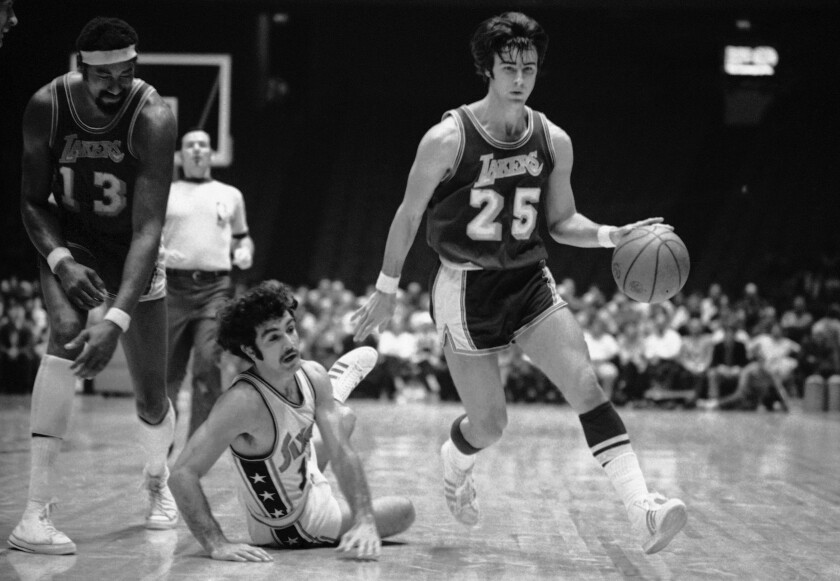 Lakers guard Gail Goodrich drives past 76ers guard Dave Wohl, who fell to the court after tripping over Wilt Chamberlain.