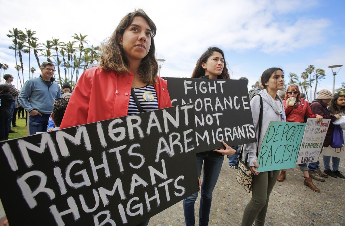 Women hold signs reading: "Immigrant rights are human rights," "Fight ignorance not immigrants," and "Deport racism."