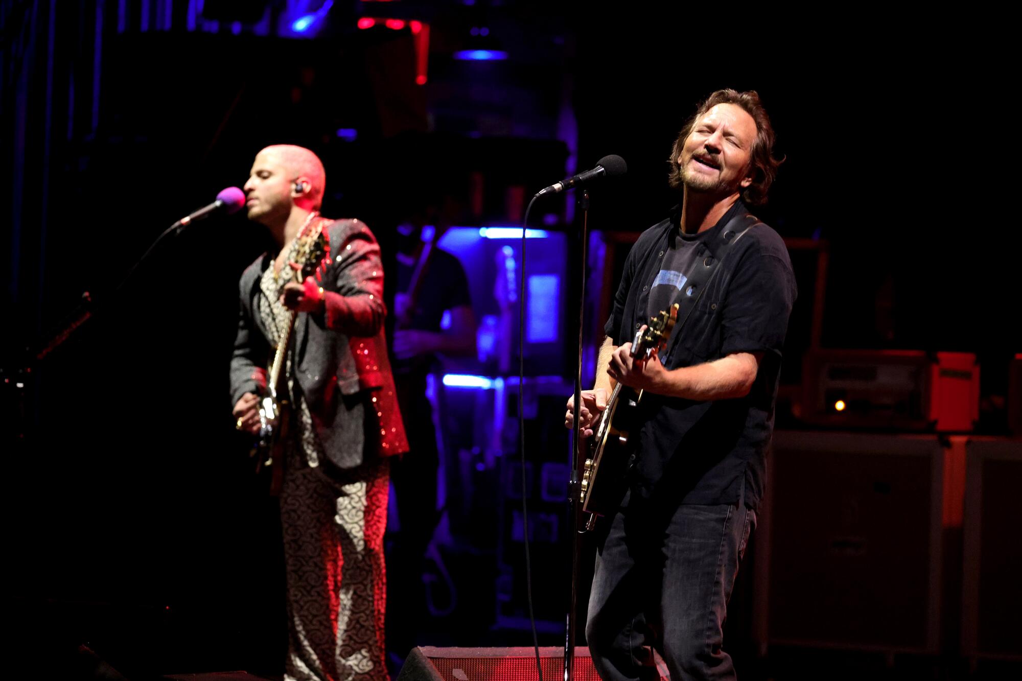 Two rock musicians perform onstage.