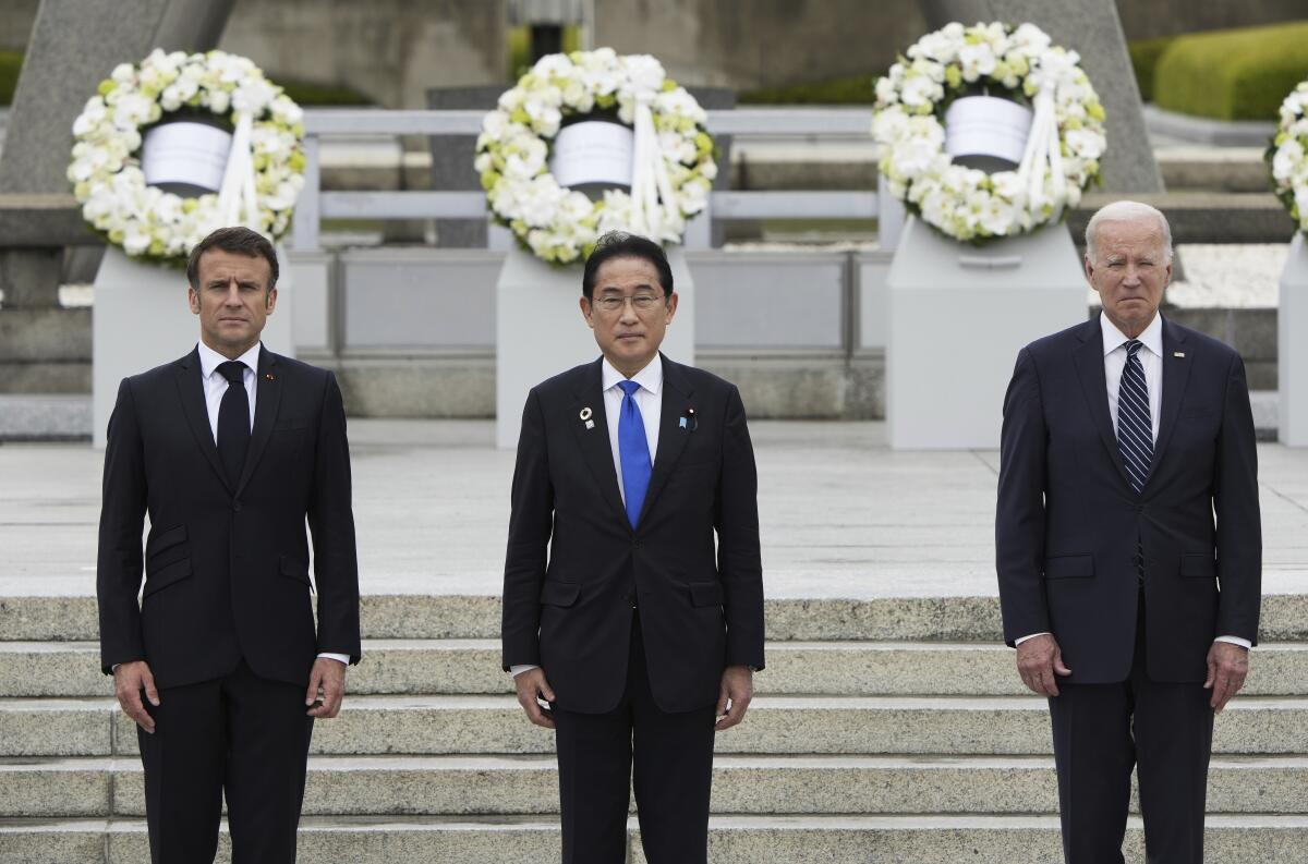 French President Emmanuel Macron,  Japanese Prime Minister Fumio Kishida and President Biden stand in front of wreaths.