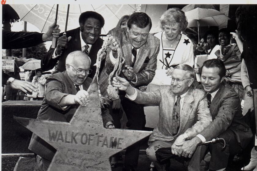 Laker announcer Chick Hearn(center) gets an assist from honory Hollywood mayor Johnny Grant.