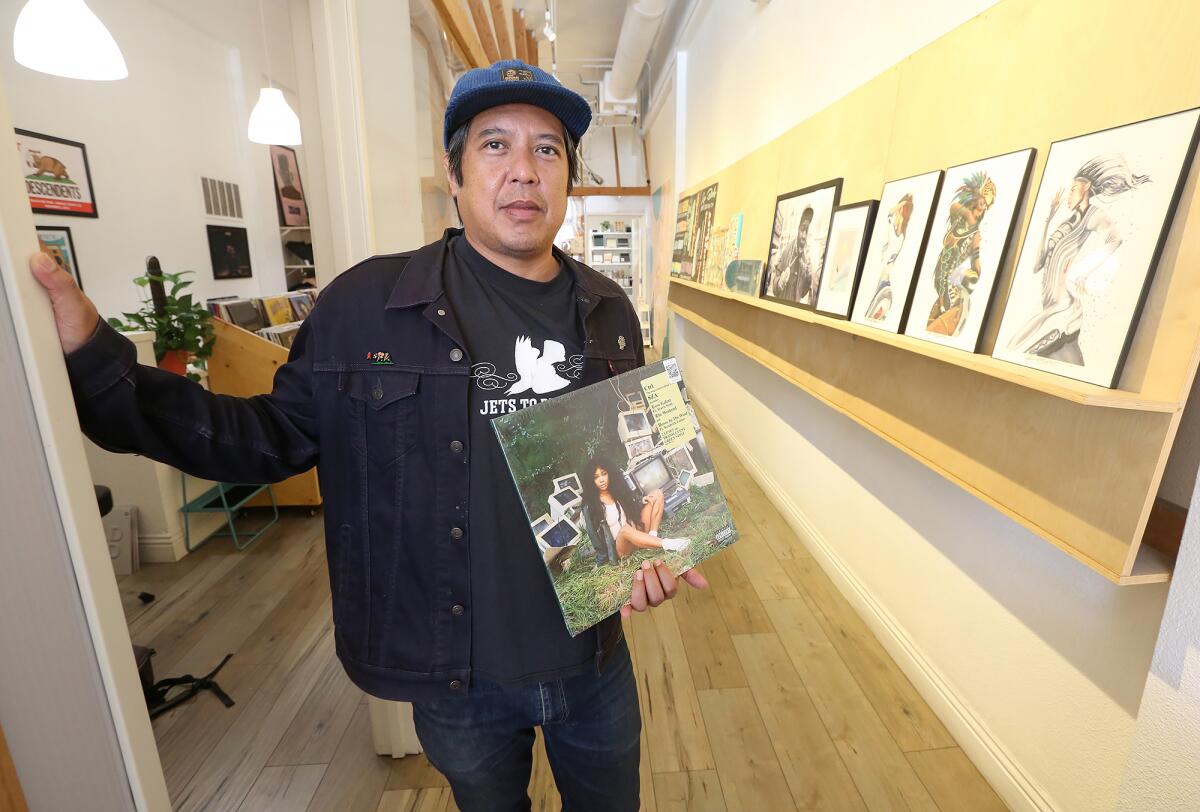 Owen Ela holds one of his favorite albums by SZA at his indie record store Resident Vinyl.