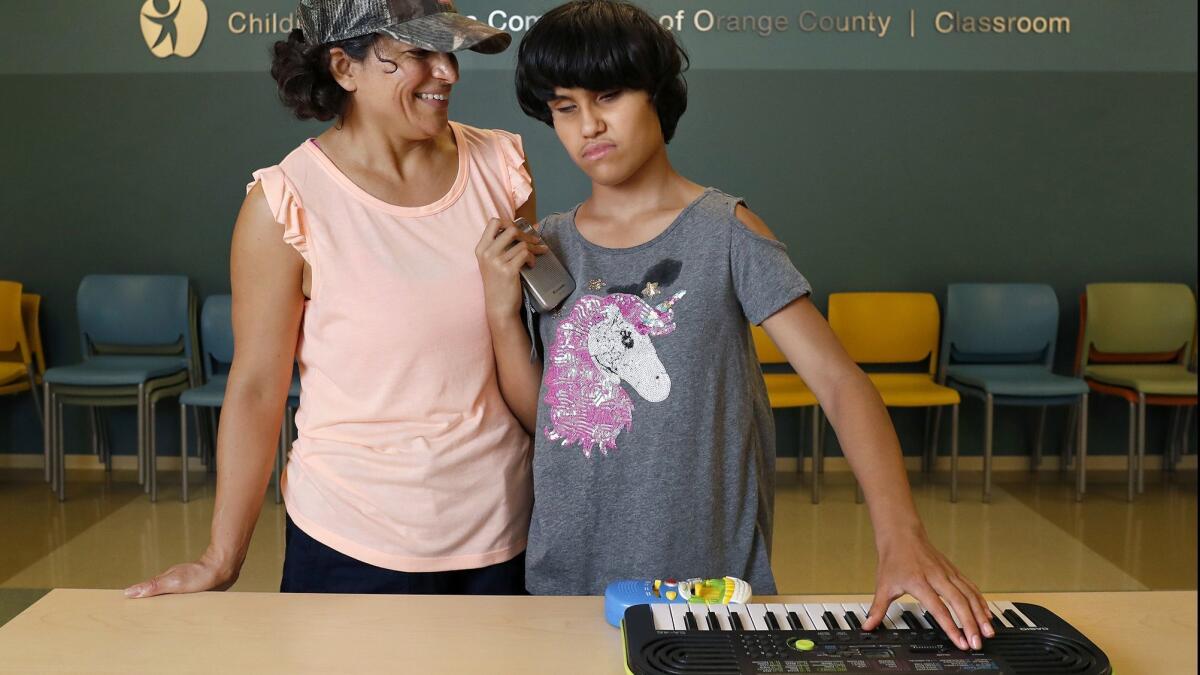 Zoe Cruz, 12, accompanied by her mother, Margaret, at the Center for Autism & Neurodevelopmental Disorders in Santa Ana. Zoe is blind, mute and severely delayed. “Music” was the first word she ever learned to sign at age 4.