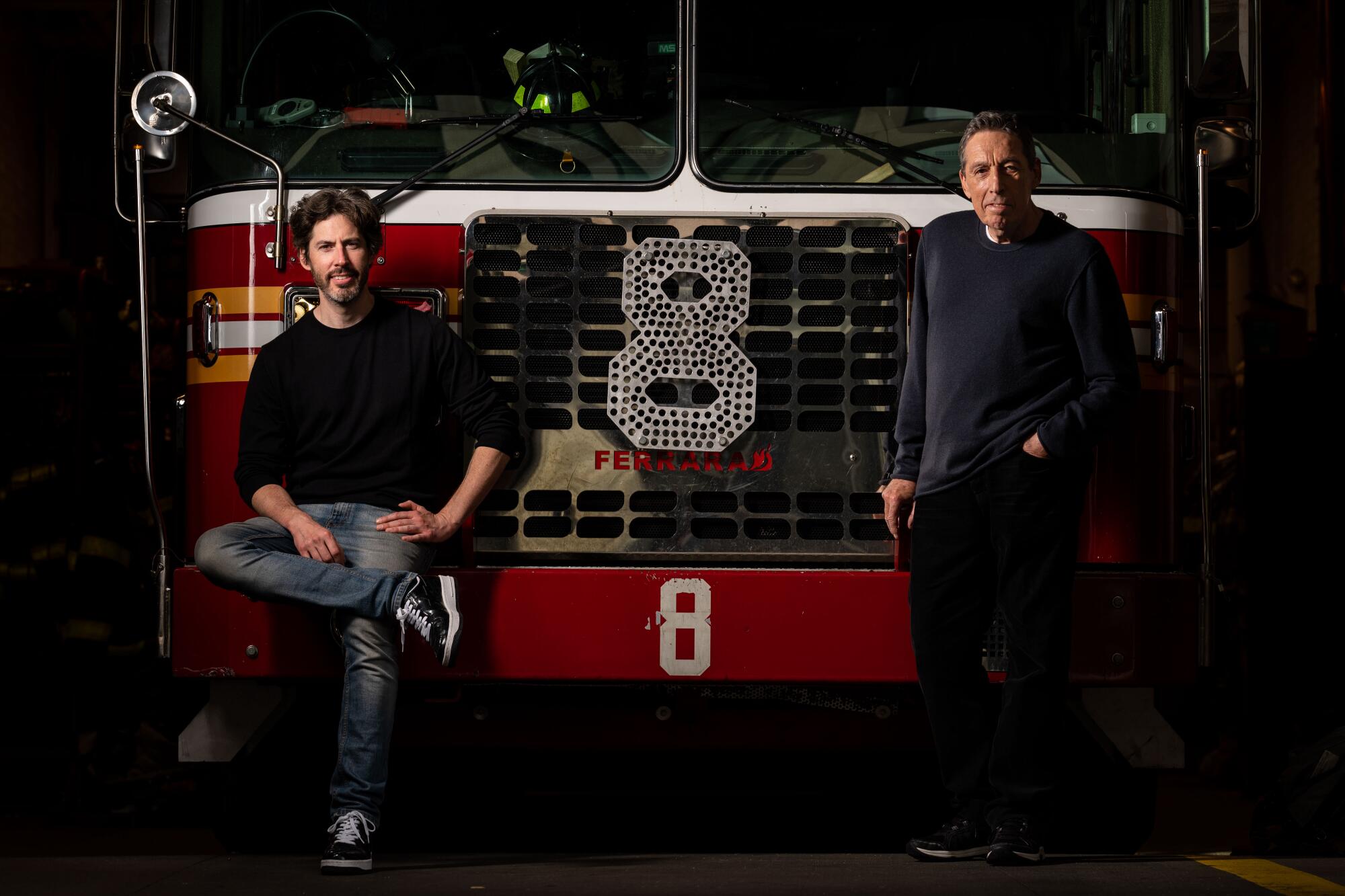 Two men pose in front of a fire truck.