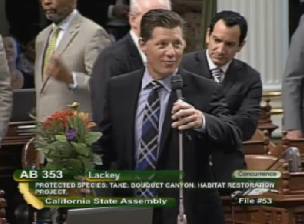 In this still image from a California Channel broadcast, Assemblyman Brian Jones (R-Santee) holds a bouquet of flowers he promptly delivered to fellow lawmaker, Tom Lackey (R-Palmdale) on the Assembly floor during debate Thursday.