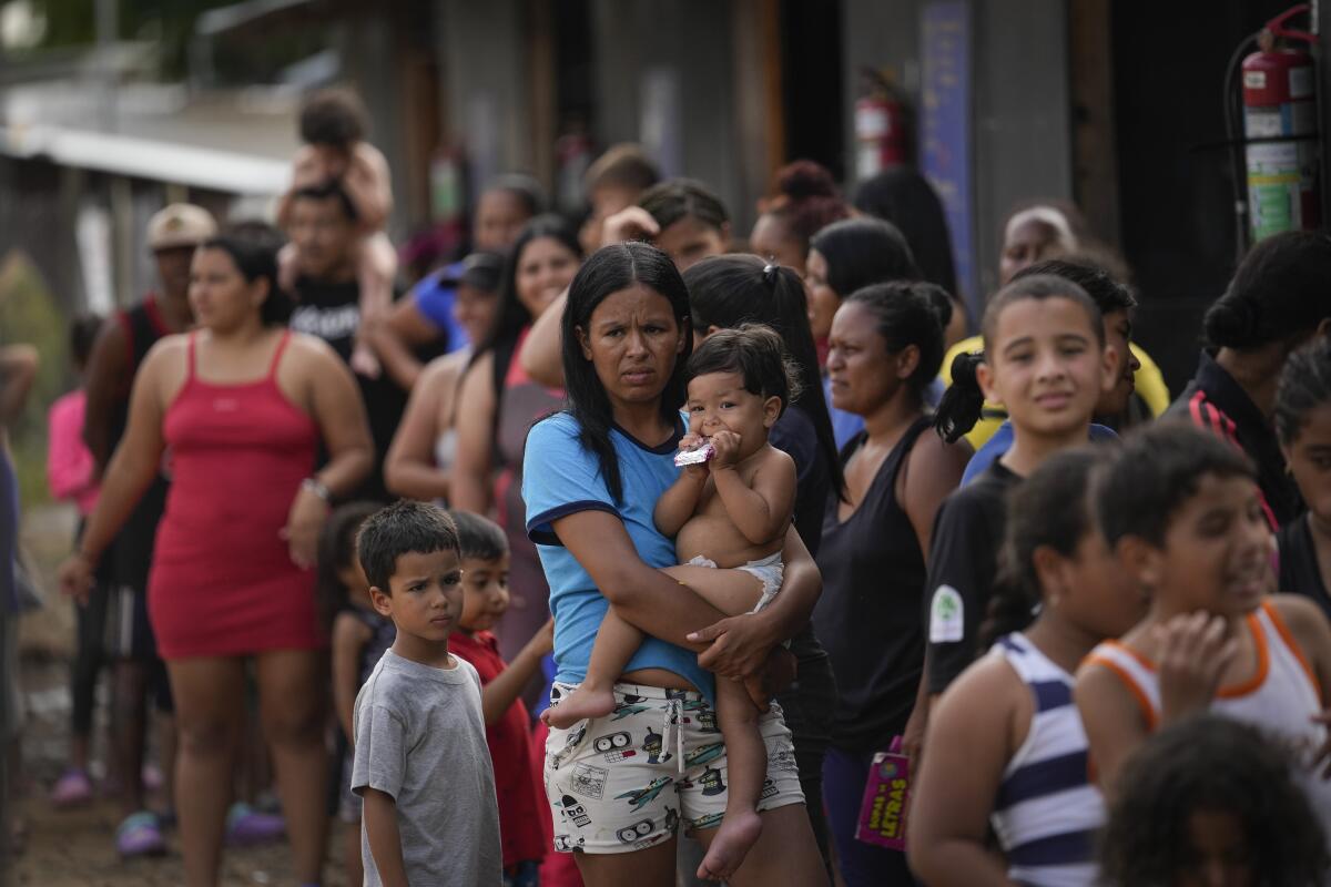 ARCHIVO - La migrante venezolana Minorca Parra sostiene a su hija Karin Alvear mientras hace fila 