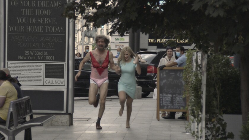 Sacha Baron Cohen, in women's underwear, and Maria Bakalova run on a city sidewalk.