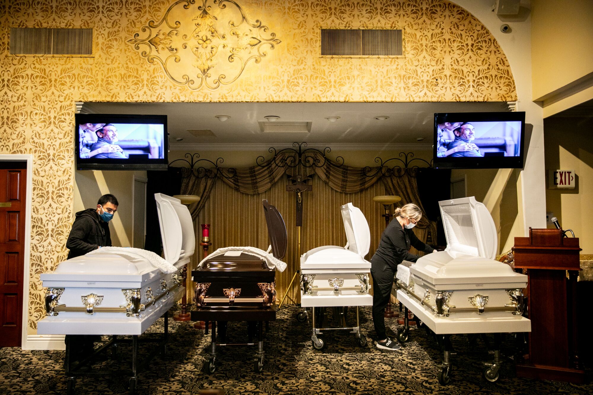 Sammy Deras, a funeral attendant, and Kristy Oliver, an embalmer and funeral director, work with caskets.