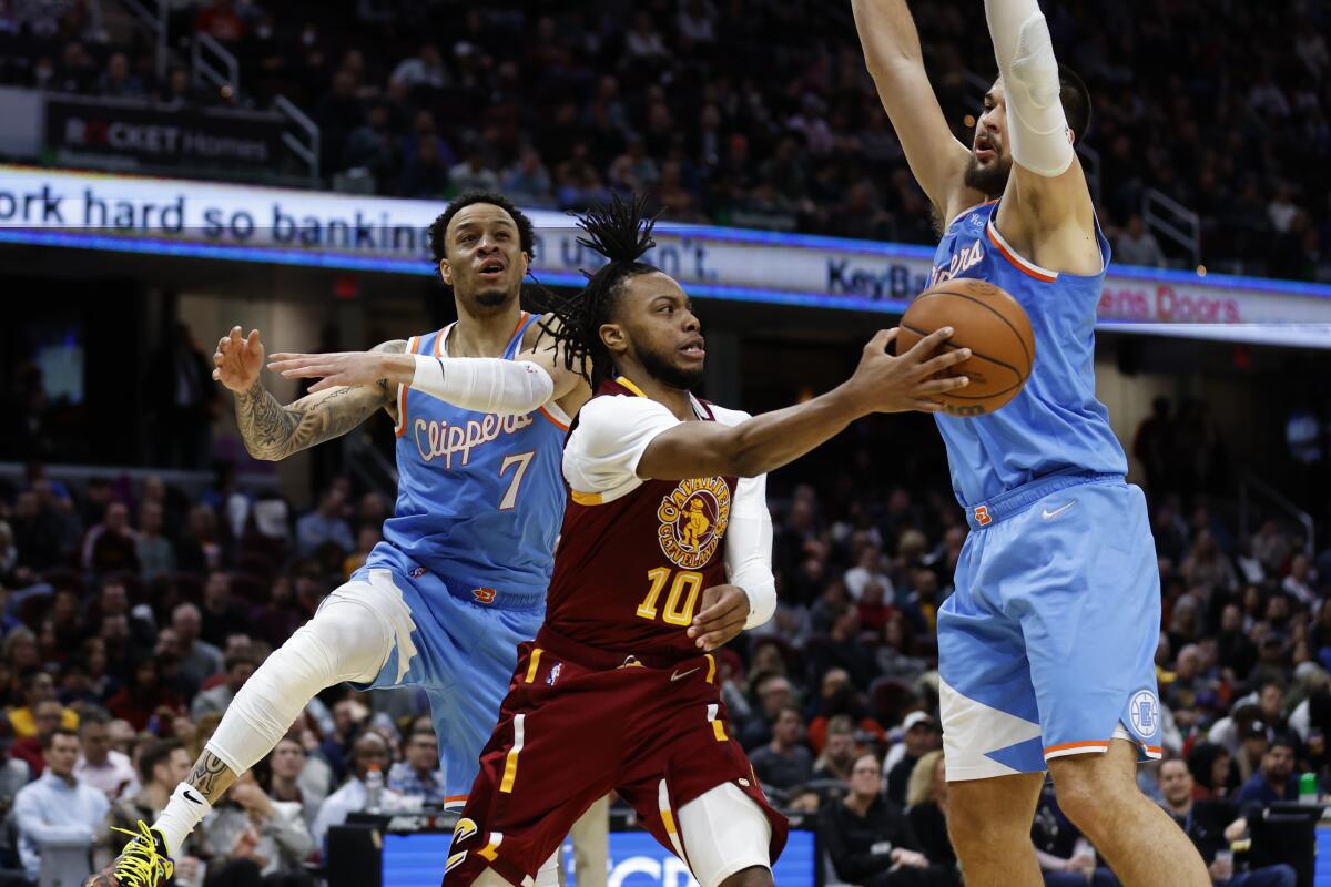 Cavaliers guard Darius Garland makes a pass after driving against Clippers defenders Amir Coffey (7) and Ivica Zubac.