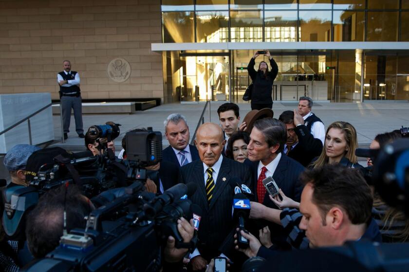 Former Los Angeles County Sheriff Lee Baca, center, talks to reporters outside court in December.