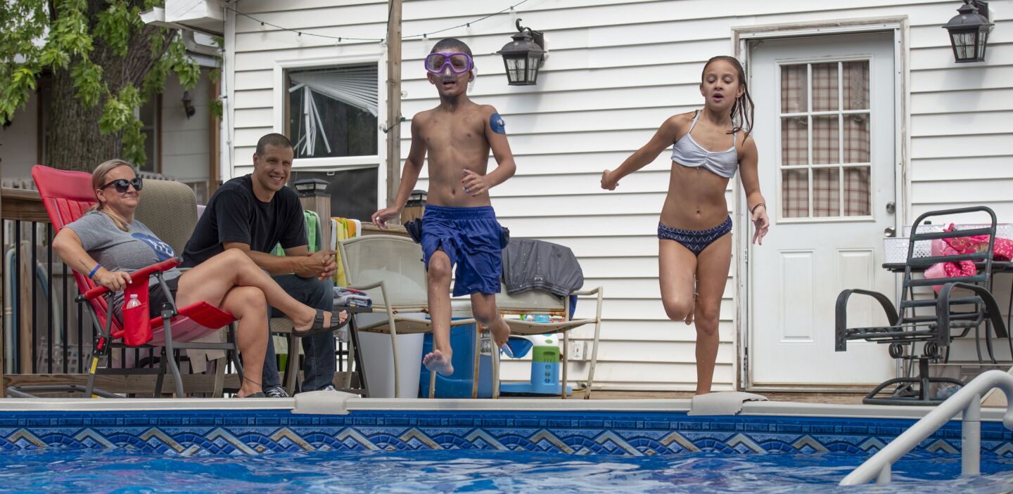 Carolyn and John Macan watch twins Bo and Brooklynn play in the family’s pool, which was donated by a local company.