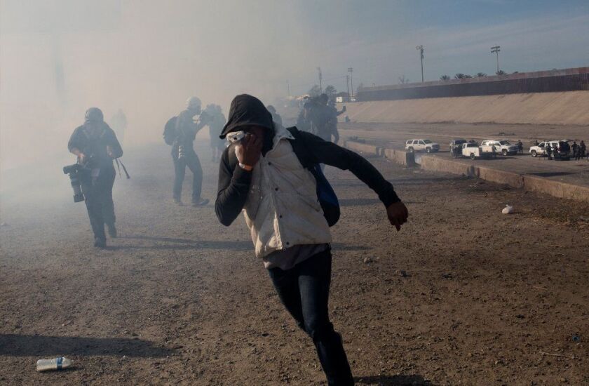 A migrant runs from tear gas launched by U.S. border agents near the the San Ysidro port of entry south of San Diego on Nov. 25.