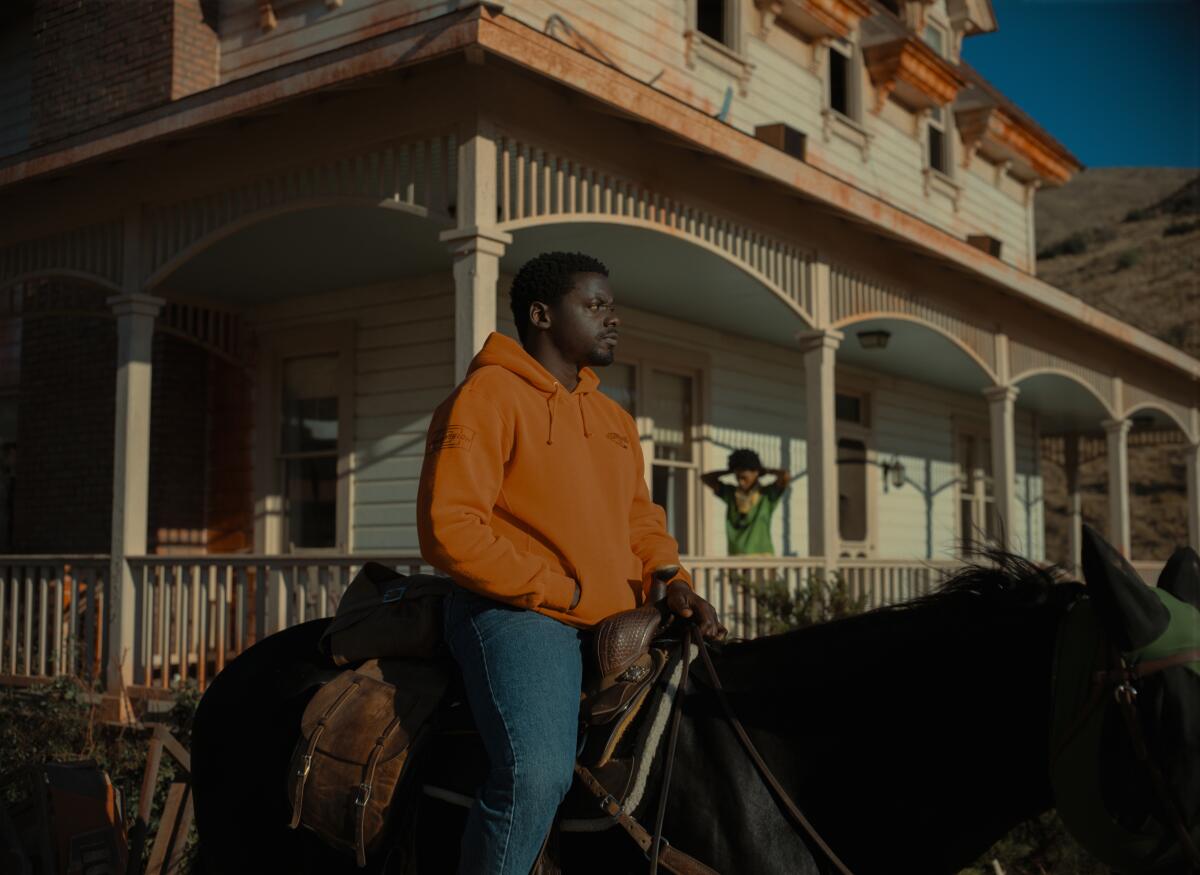 Daniel Kaluuya, in jeans and a hoody, sits atop a horse in a scene from "Nope."