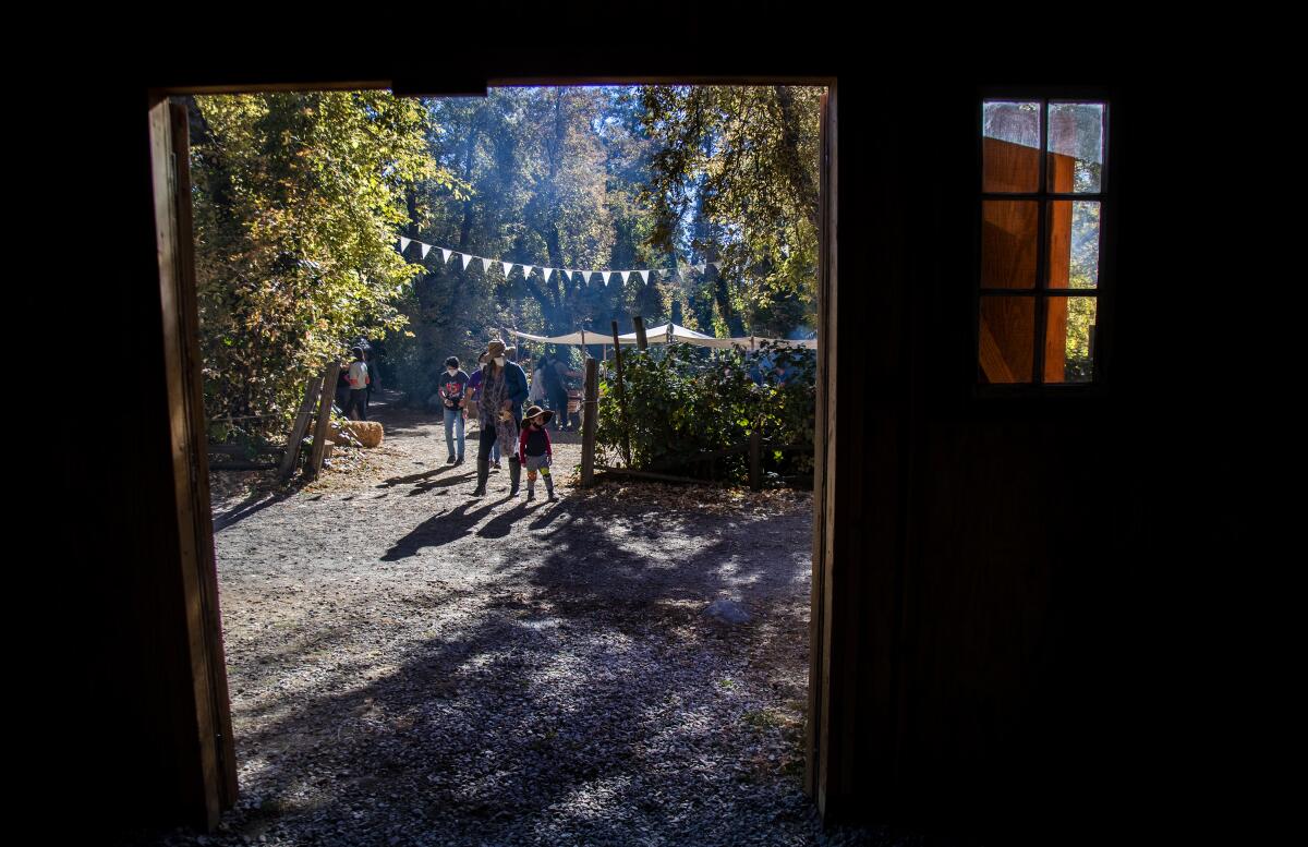 People walk along an outdoor path framed in the doorway of a barn.