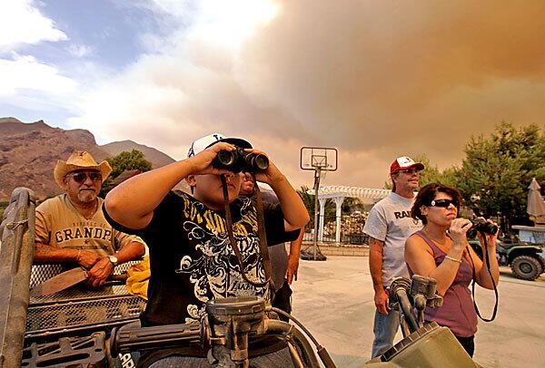 Arnold Torrez,73, left, Joseph Rini, 11, and Scott and Rosanne Wright watch the Station fire creep up the mountains not far from their hilltop home on Olson Road in Acton.