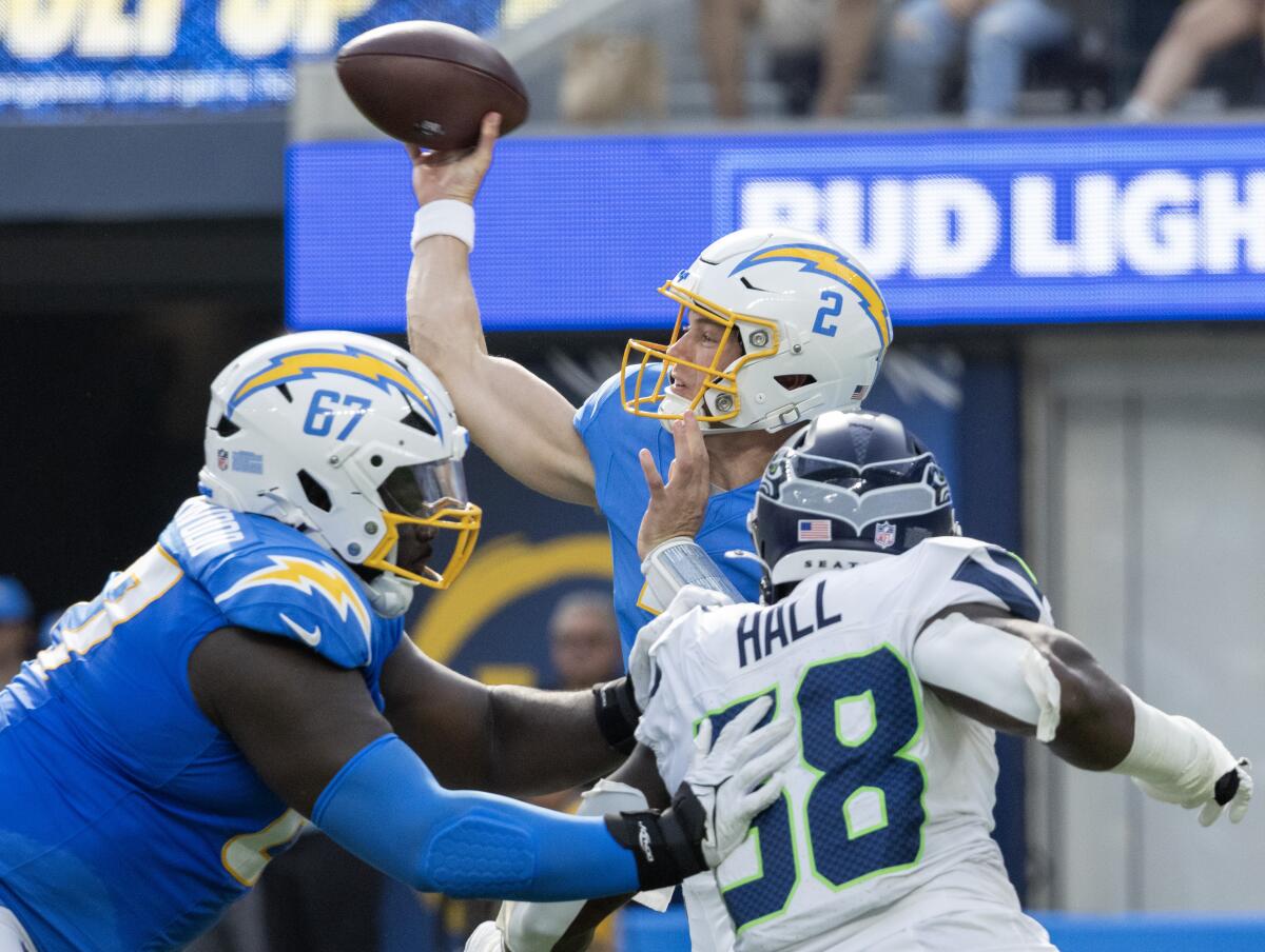 Chargers quarterback Easton Stick tries to get rid of the ball under pressure from Seahawks linebacker Derick Hall.