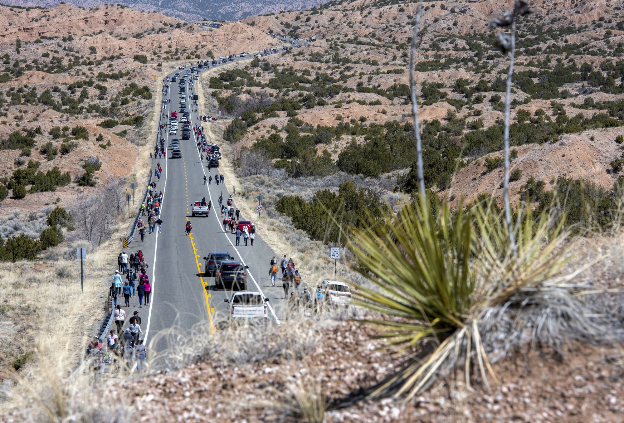 People walk and drive along Santa Fe County Road during a pilgrimage