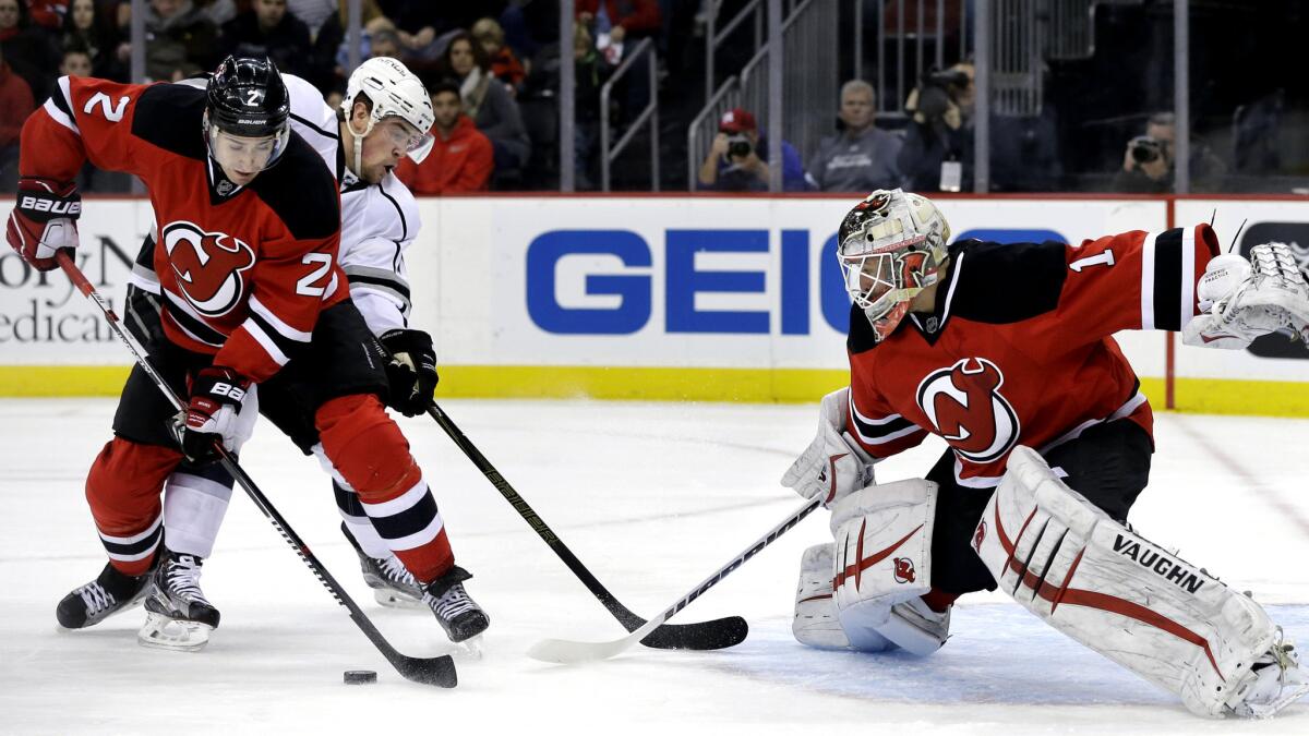Devils defenseman John Moore (2) tries to clear the puck away from Kings left wing Tanner Pearson (70), who is looking for a shot against Devils goalie Keith Kinkaid (1) in the first period Sunday.