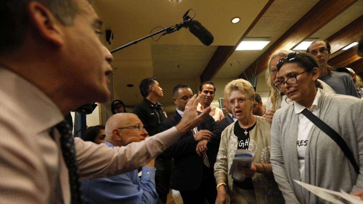 Angry residents and property owners spar with Mayor Eric Garretti, left, and Councilman Mike Bonin, second from left, during a town hall last week at Westminster Elementary School over plans for homeless housing in Venice.