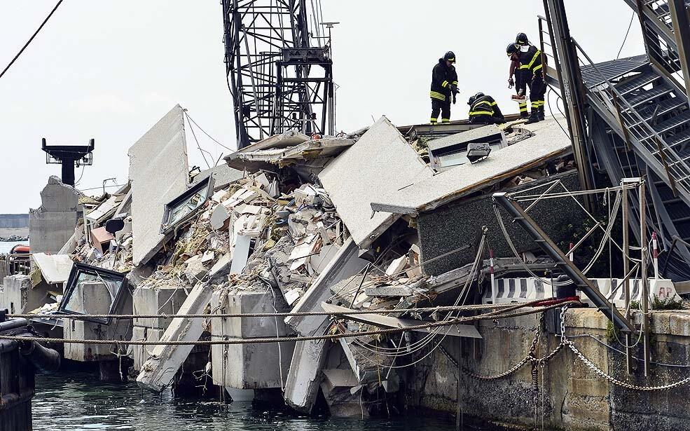 Rescue workers inspect the scene of a damaged control tower in the port of Genoa after a container ship smashed into the tower, leaving at least seven people dead and several missing in the nighttime accident.