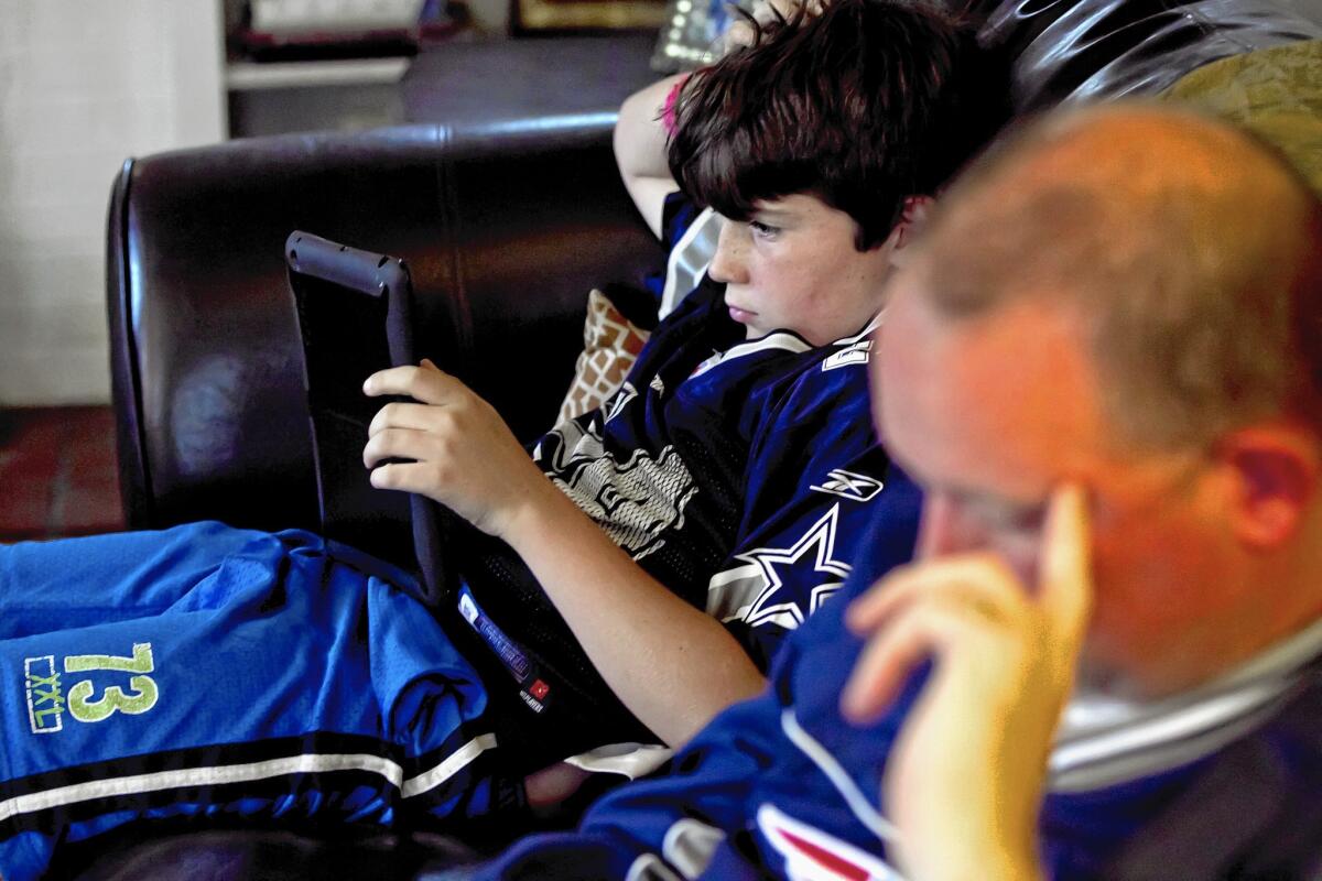 Streaming NFL games would allow Facebook to create content before and after the games. Above, 11-year-old Theo Kennedy looks at stats on an iPad while his father, Sean, looks at his stats on his iPhone as they watch NFL football.