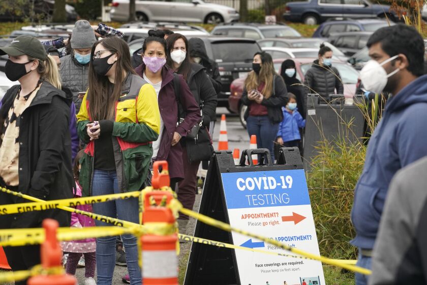 People line up to be tested for the coronavirus at a free testing site Wednesday, Nov. 18, 2020, in Seattle. The Washington state Department of Health has reported 2,589 additional COVID-19 cases and 23 more deaths, setting another new record. The previous record was set Sunday with 2,519 cases. (AP Photo/Elaine Thompson)