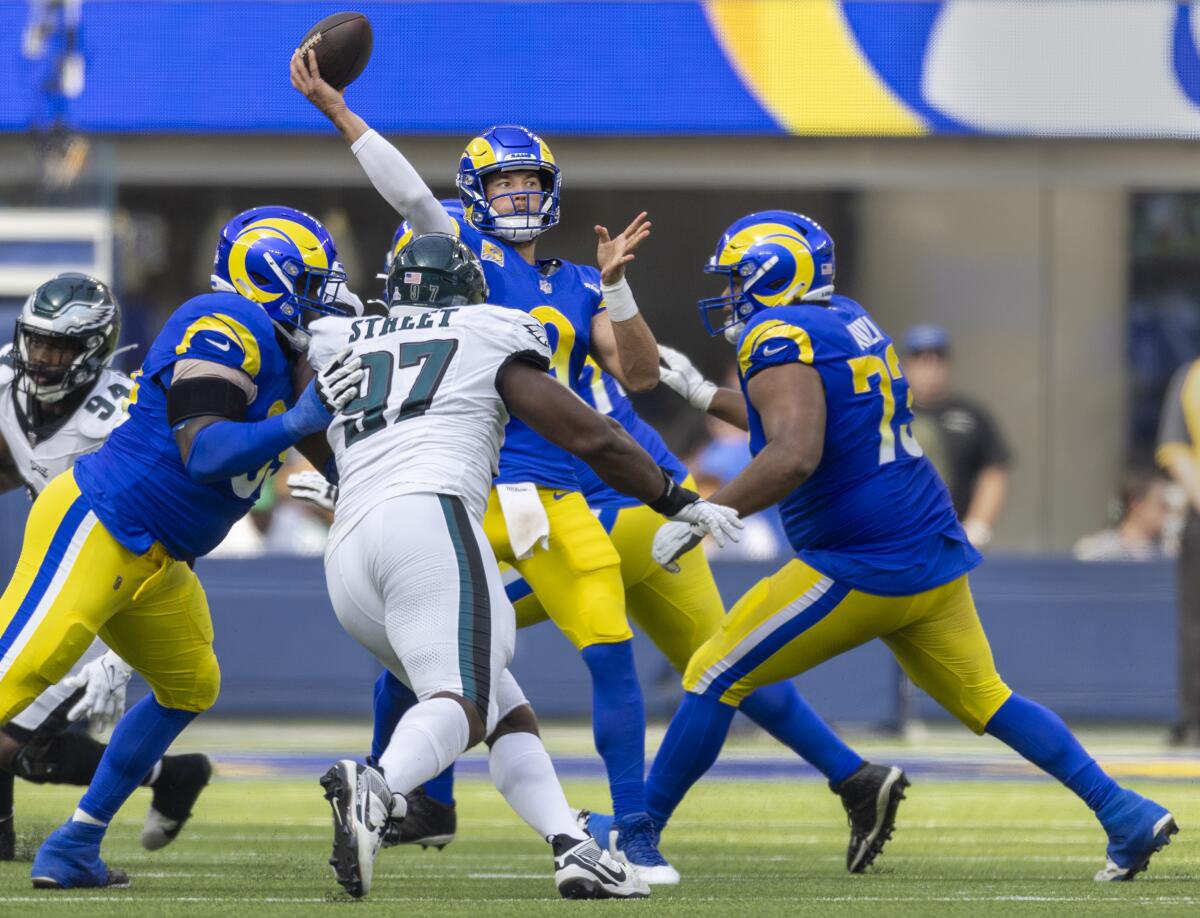 Rams quarterback Matthew Stafford throws the ball under pressure from an Eagles pass rush.