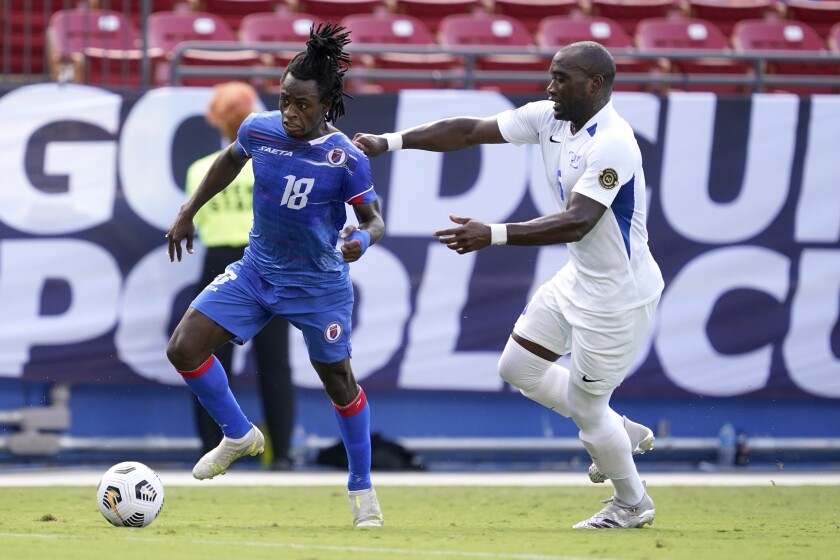 Haiti forward Ronaldo Damus (18) is held by Martinique defender Jean-sylvain Babin during a CONCACAF Gold Cup Group A match 