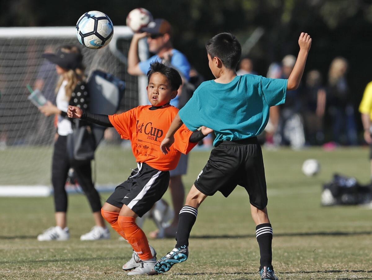Davis Elementary's Jack Kondo, left, tracks down a ball during a boys' third- and fourth-grade Gold Division pool-play match against Mariners Christian School at the Daily Pilot Cup on Wednesday.