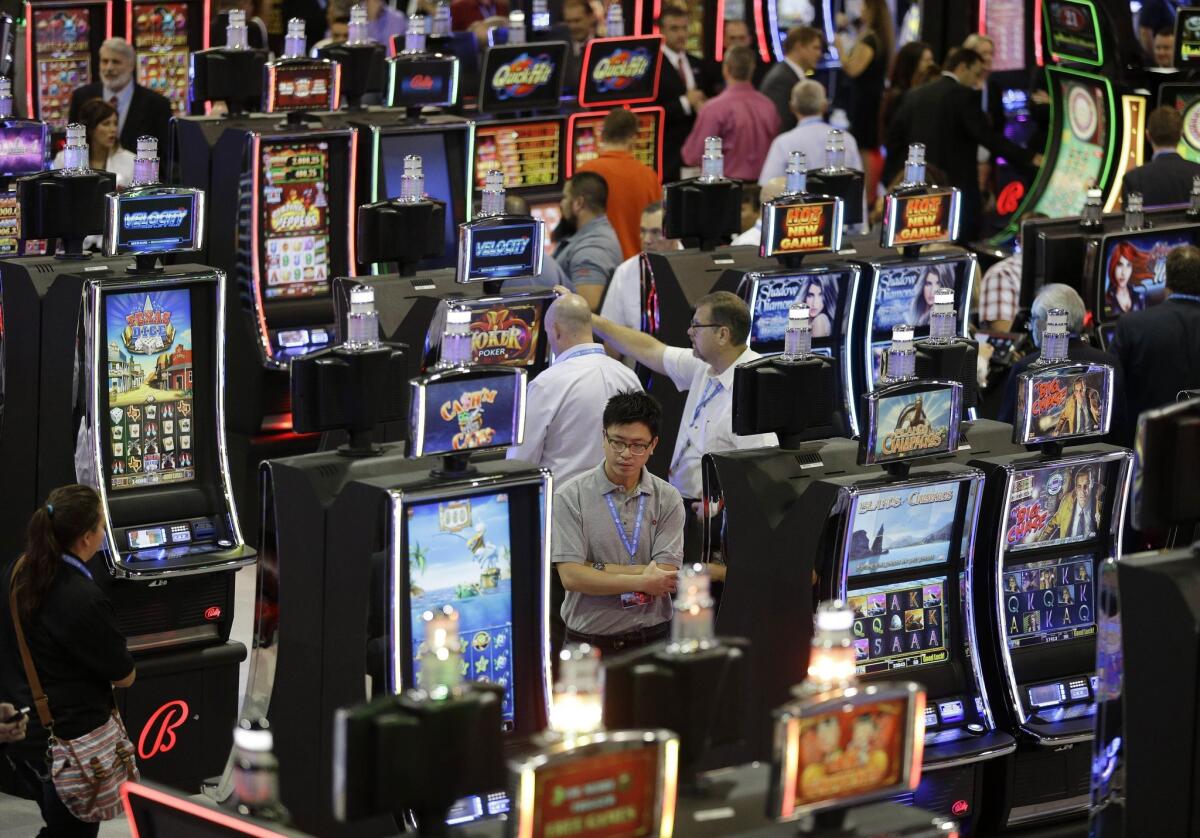 FILE - In this Sept. 30, 2015 file photo, people look at slot machines at the Ballys Technology booth during the Global Gaming Expo in Las Vegas. The gambling industry is trying to attract younger players to the casino floor to revive revenues that have sagged in recent years. (AP Photo/John Locher, File)