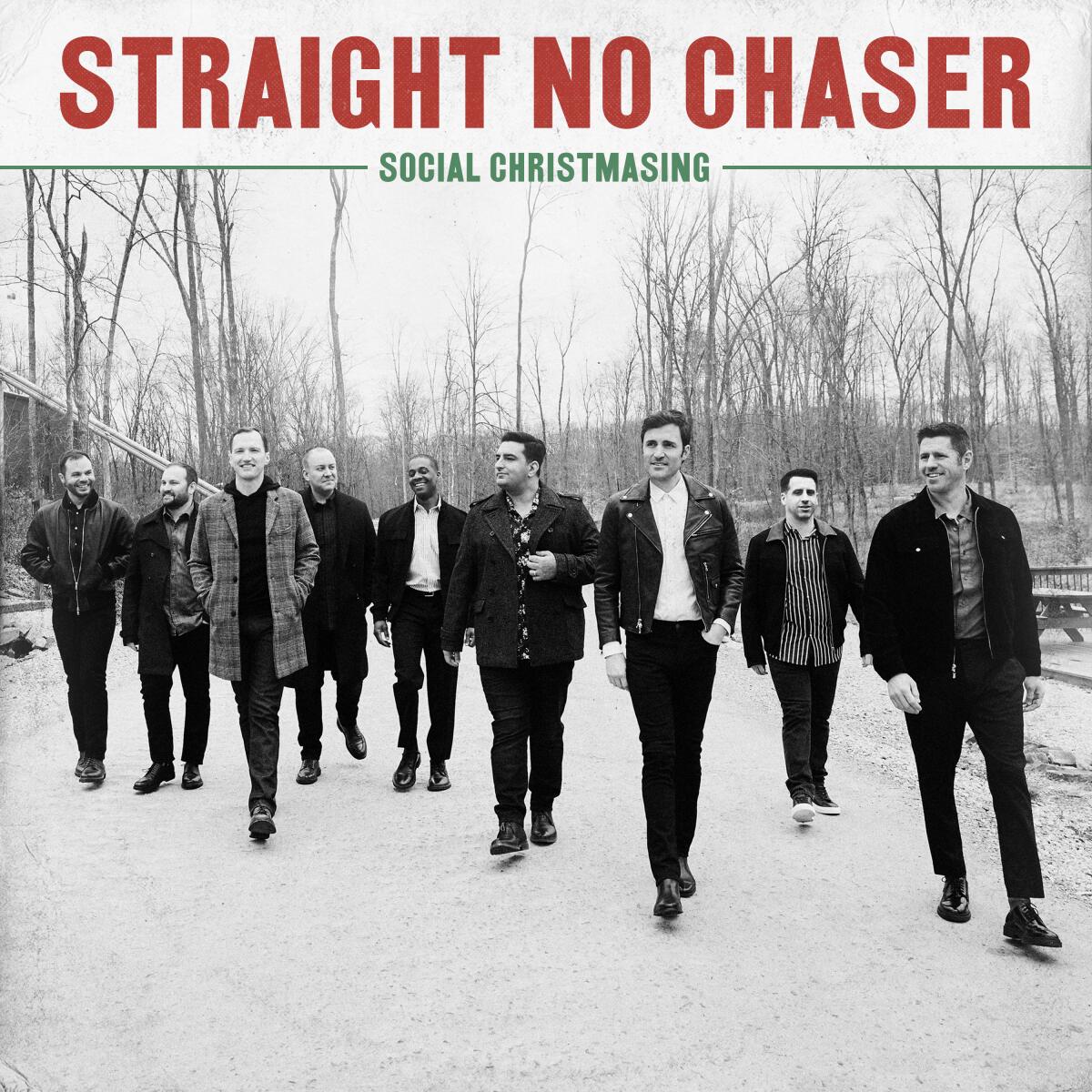 Nine men walk on a snowy road, bare trees in the background, on an album cover.