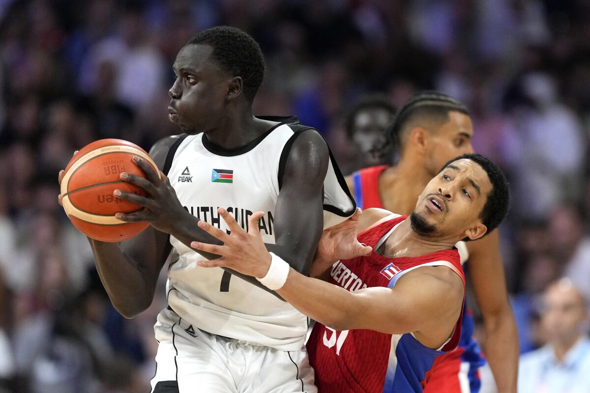 Tremont Waters, right, of Puerto Rico, reaches in on Bul Kuol, of South Sudan.