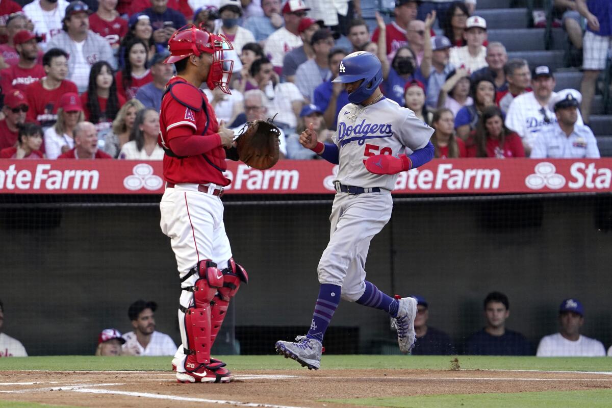 The Dodgers' Mookie Betts scores on Freddie Freeman's single July 15, 2022. Angels catcher Kurt Suzuki is at left.
