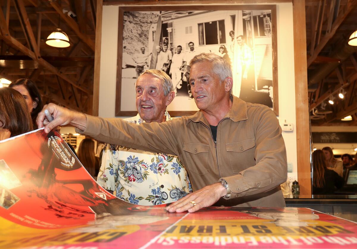 Surfing pioneer Dick Metz, left, and director Richard Yelland autograph posters.