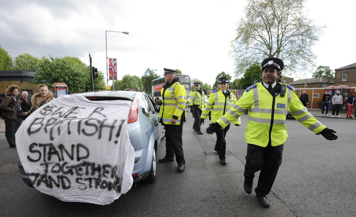 British police officers stop a car carrying a banner saying 'We are British, stand together, stand strong' outside the Royal Artillery Barracks in the southeast London district of Woolwich, close to where a soldier was killed.