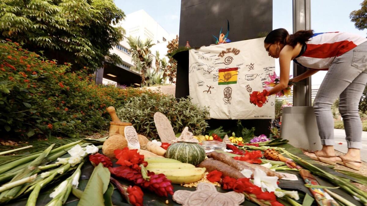 Soraya Medina works on an art installation next to the Christopher Columbus statue in Grand Park during Indigenous Peoples Day. The statue was boxed recently and will remain so until it is moved to a new location.