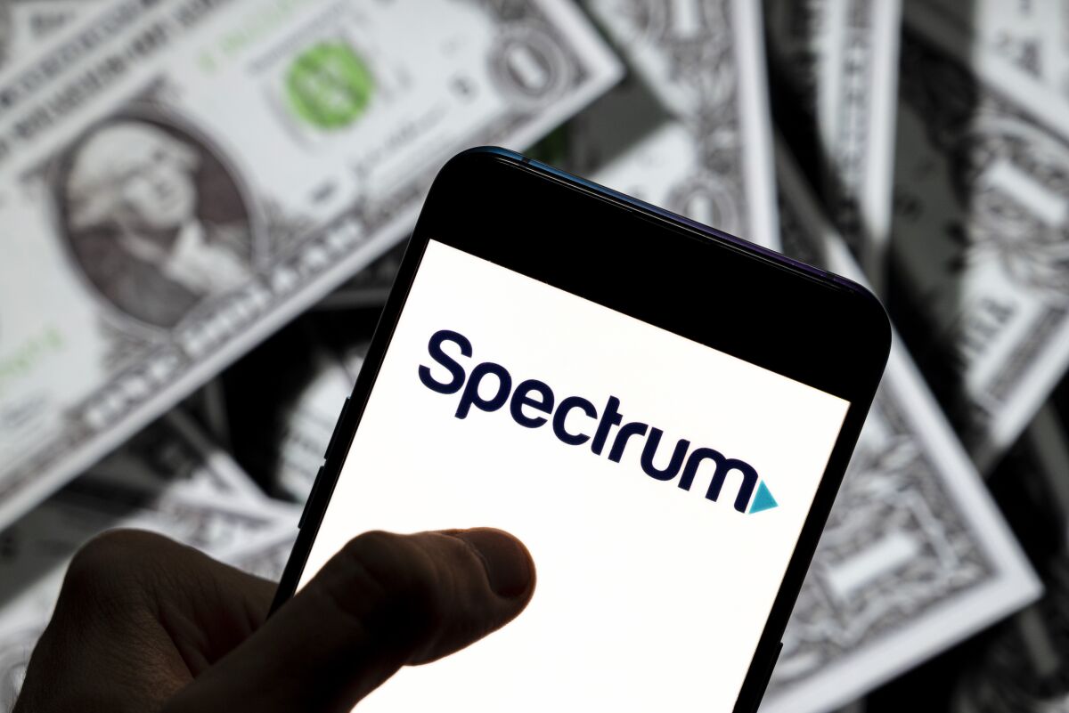 The Spectrum logo is displayed on a smartphone with U.S. currency in the background.