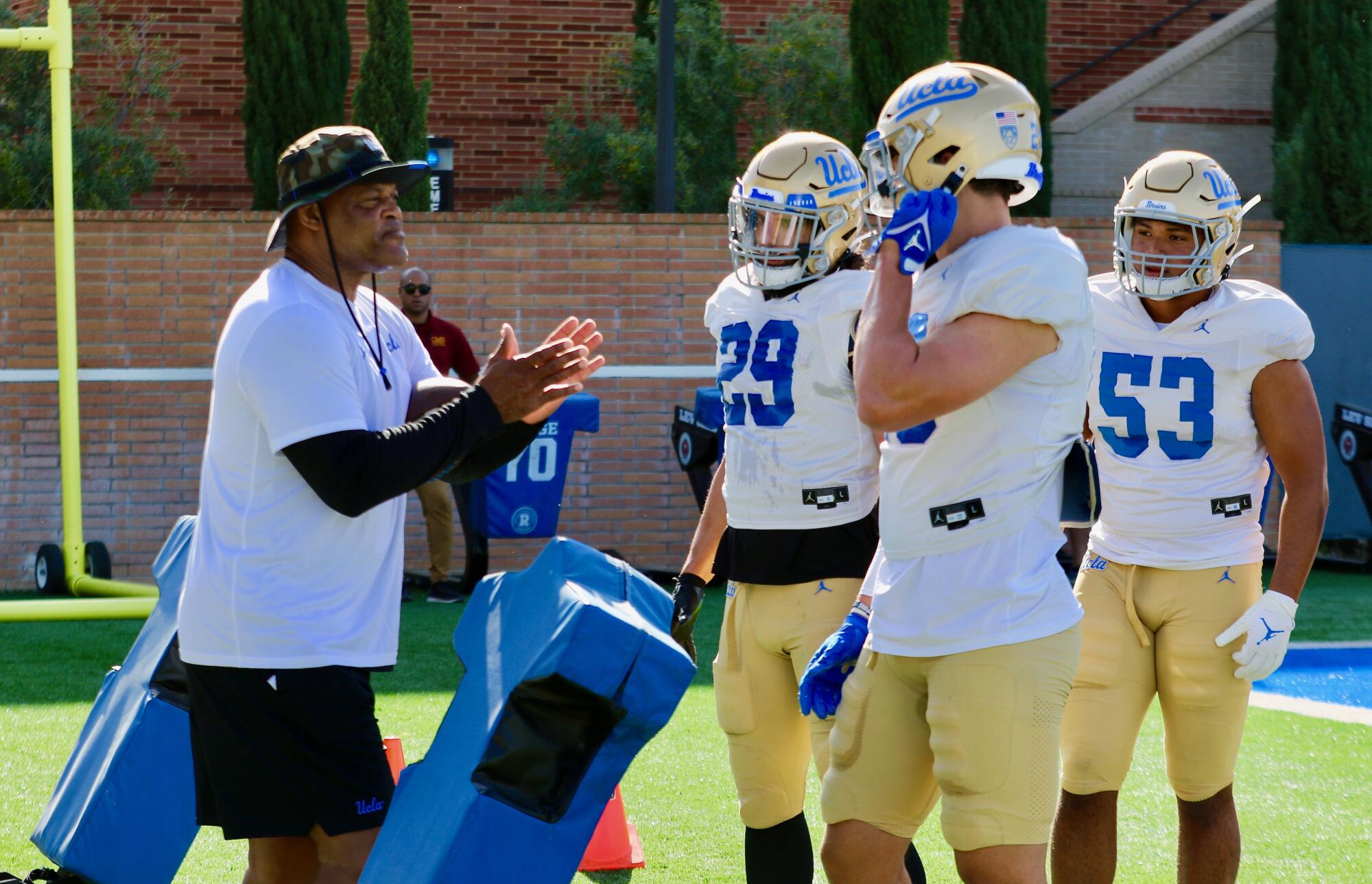 UCLA defans antrenörü Ken Norton Jr. defans oyuncuları Adam Cohen, Kain Medrano ve Darius Muasau ile konuşuyor.