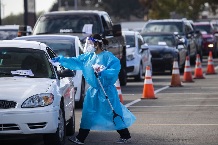 A 360 Clinic health care worker conducts testing at a drive-through site in Costa Mesa.