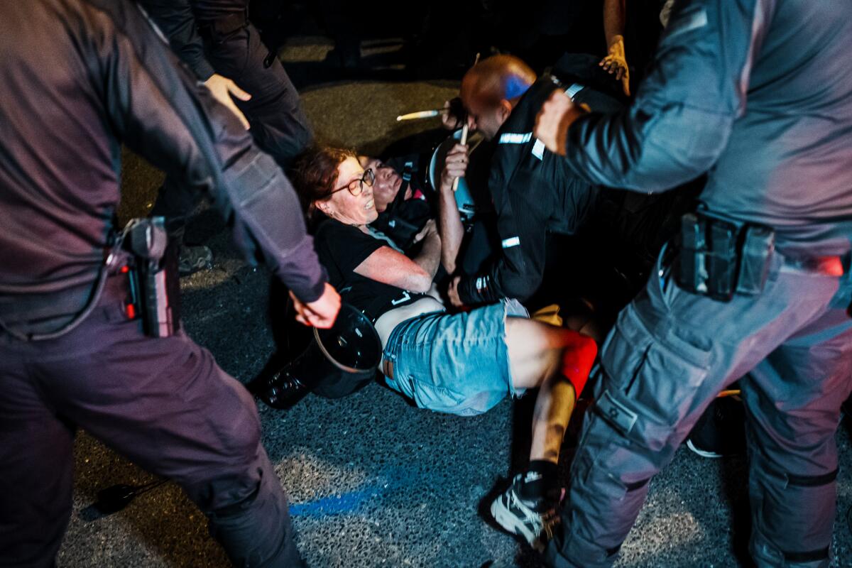 Protesters fall to the ground as police push back the crowd from gathering near a roadway.