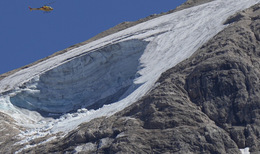 A rescue helicopter hoovers over the Punta Rocca glacier near Canazei, in the Italian Alps in northern Italy, Monday, July 4, 2022, a day after a huge chunk of the glacier broke loose, sending an avalanche of ice, snow, and rocks onto hikers. Rescuers said conditions downslope from the glacier, which has been melting for decades, were still too unstable to immediately send rescuers and dogs into the area to look for others buried under tons of debris. (AP Photo/Luca Bruno)