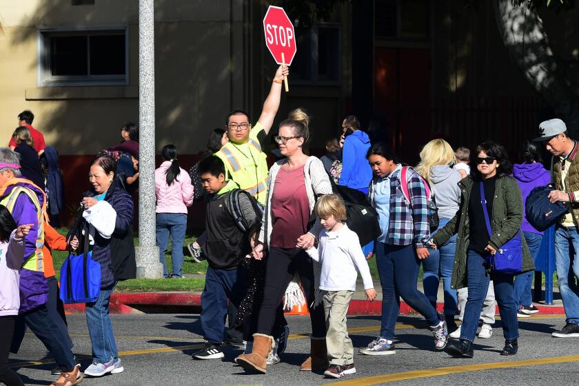 An Alhambra Unified School District crossing guard stops traffic for parents picking up their children from Ramona Elementary School on February 4, 2020 in Alhambra, California. - As the coronavirus outbreak spreads, fuelling rumors and misinformation, a petition to cancel all classes in one US school district for fear of the virus has garnered nearly 14,000 signatures. The online petition posted on Change.org urges the Alhambra Unified School District located east of Los Angeles and with a heavily Asian population, to basically shut down until the outbreak is over. School district officials, however, have dismissed the petition as a bid to whip up hysteria over the deadly outbreak that has killed hundreds in China. (Photo by Frederic J. BROWN / AFP) (Photo by FREDERIC J. BROWN/AFP via Getty Images)