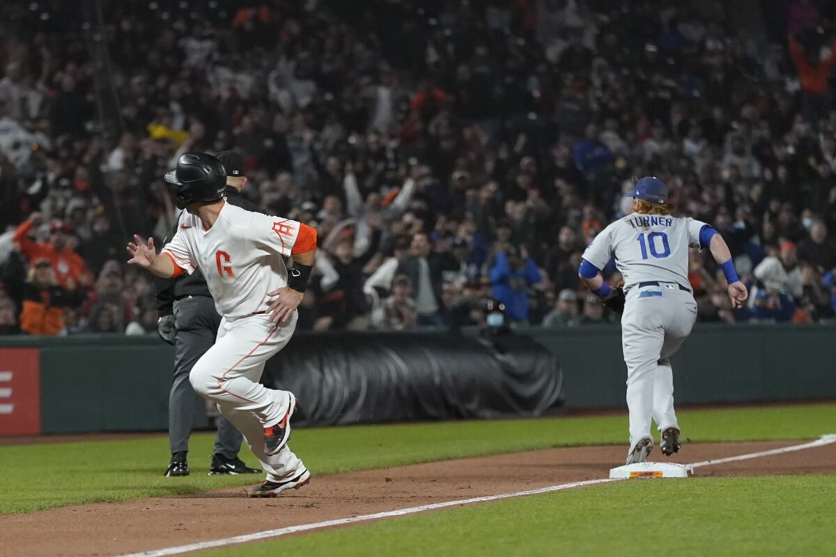 San Francisco Giants' Buster Posey, left, runs home to score as Dodgers third baseman Justin Turner (10) looks for the ball