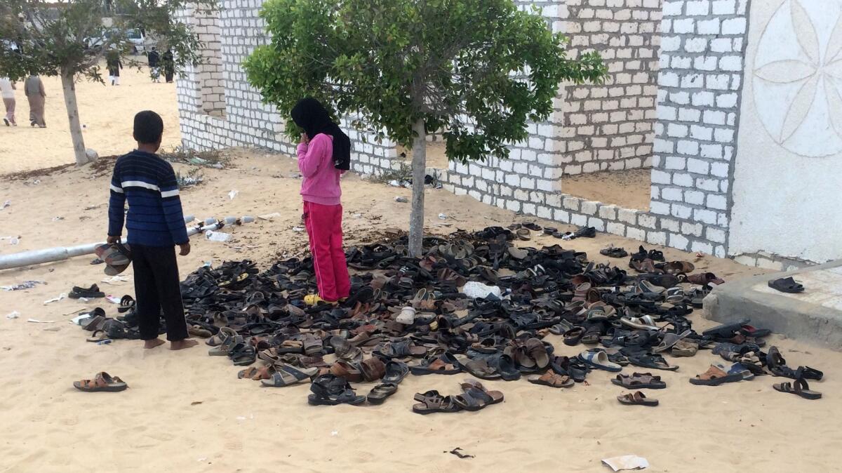 Egyptian children stand near a pile of footwear belonging to the victims of the attack that targeted the Rawda mosque.