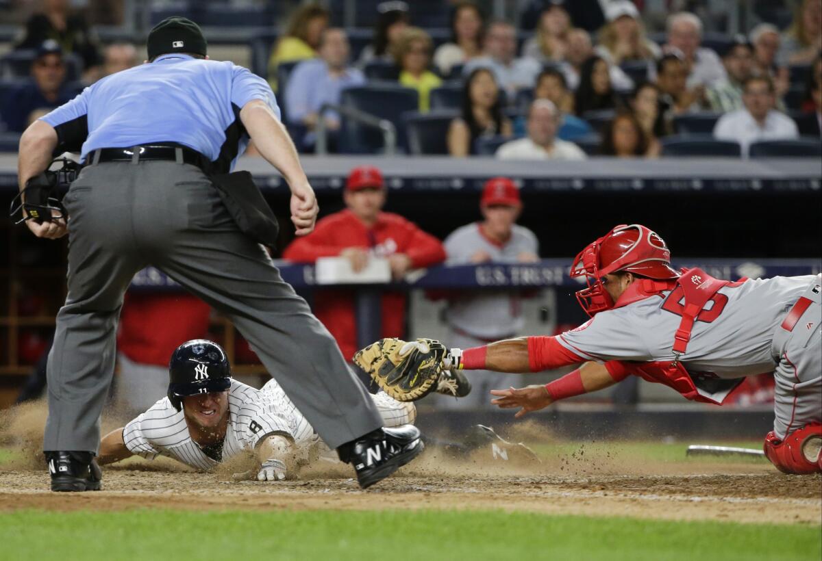 Yankees outfielder Brett Gardner (11) slides past Angels catcher Carlos Perez to score on an Alex Rodriguez single during the seventh inning.