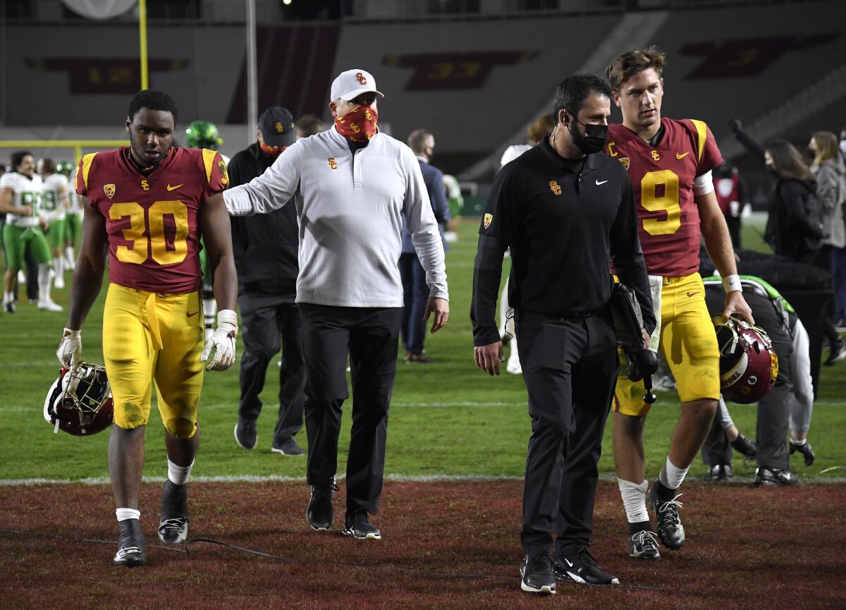 USC coach Clay Helton, center, walks off the field with Markese Stepp, left, and Kedon Slovis.